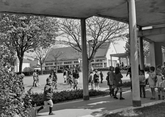 Photographie en noir et blanc représentant des enfants jouant dans la cour d'une école pendant la reconstruction de Saint-Nazaire.