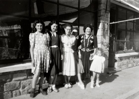 Photographie en noir et blanc représentant un groupe de femmes posant devant un commerce du centre commercial provisoire Marceau.