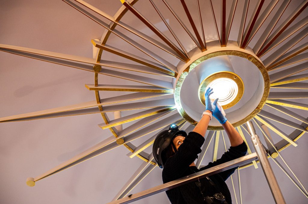 Une professionnelle de musée dépoussière un luminaire de Gilbert Poillerat provenant du salon fumoir du paquebot France (1962).