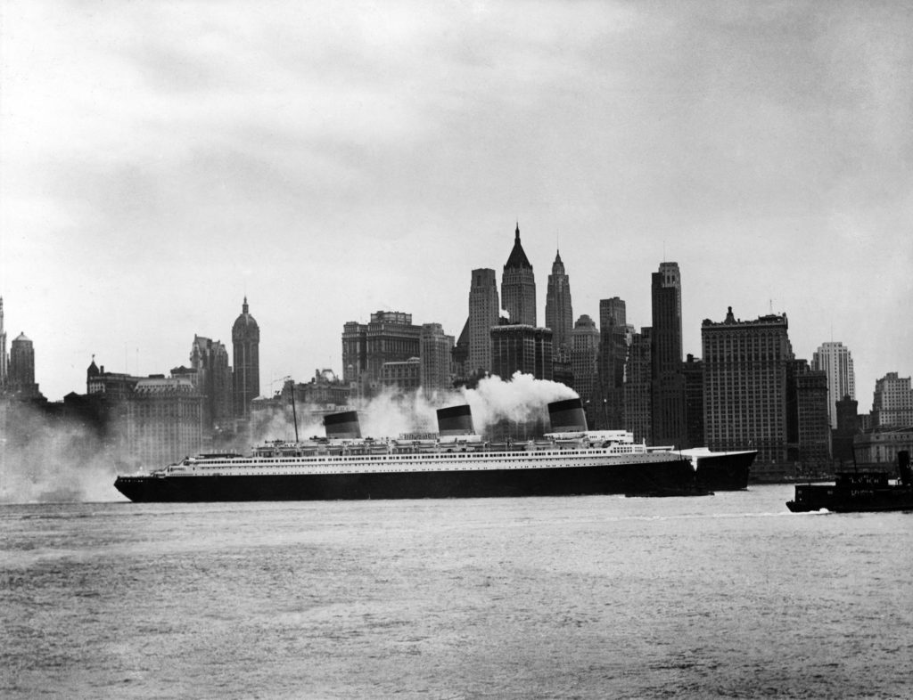 Photographie en noir et blanc représentant le paquebot Normandie devant les immeubles à New York.