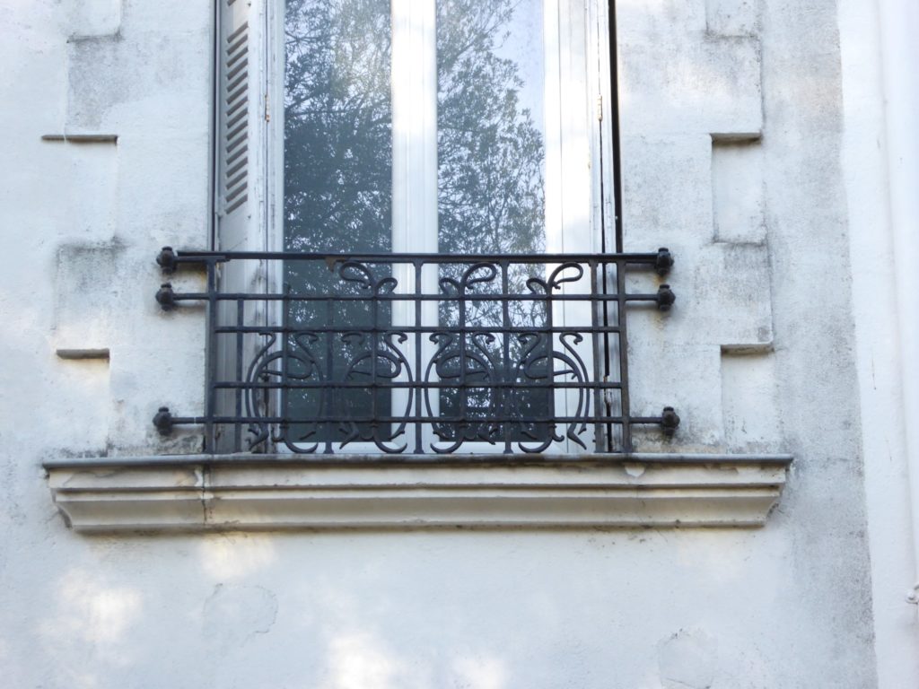Photographie d'une grille appui de fenêtre en fer forgé.