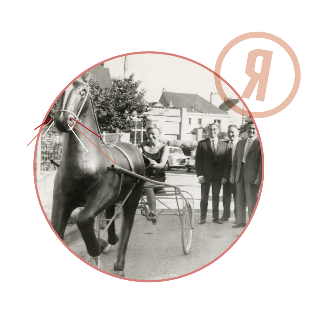 Photographie en noir et blanc représentant une femme sur une fausse calèche avec un cheval de bois.