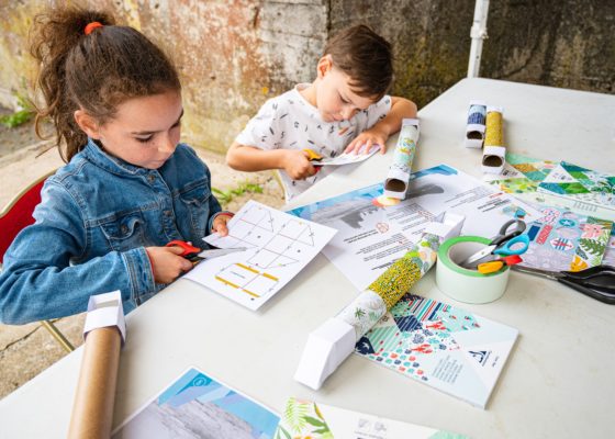 Une petite fille et un petit garçon utilisent des ciseaux lors d'un atelier créatif sur le sous-marin Espadon.
