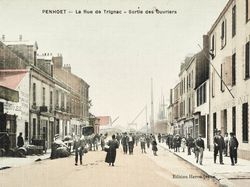 Carte postale colorisée représentant la rue de Trignac très fréquentée lors de la sortie des ouvriers des chantiers dans le quartier de Penhoët.