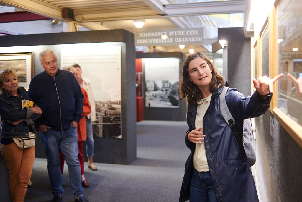 Guide montrant une œuvre à un groupe de visiteurs pendant une visite de l'Écomusée.