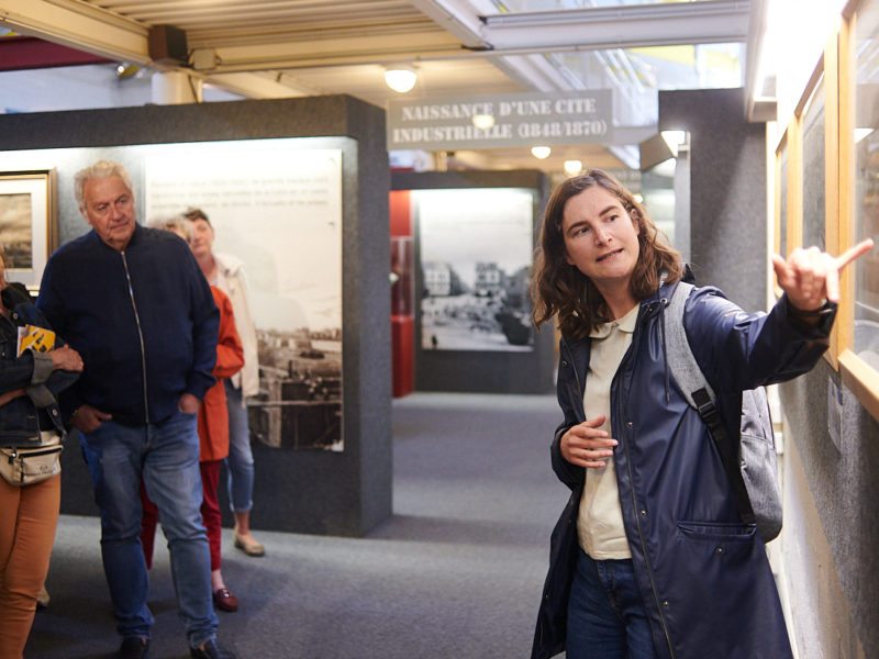 Guide montrant une œuvre à un groupe de visiteurs pendant une visite de l'Écomusée.