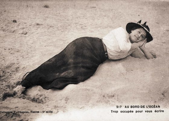 Photographe : inconnu. Éditeur : F. Chapeau. Collection particulière Odile Hameline-Bertho. Cliché Saint-Nazaire Agglomération Tourisme - Écomusée. Carte postale souvenir représentant une jeune femme allongée sur la plage. La légende de la carte indique : "au bord de l'océan, trop occupée pour vous écrire".
