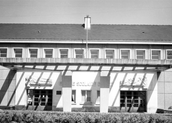 Photographie noir et blanc de la façade de l'école Carnot avec les deux bas-reliefs de Roger Prat.