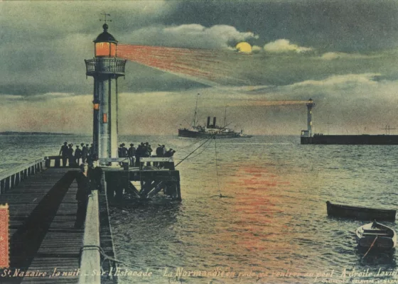 Carte postale illustrée représentant l'une des estacades de l'entrée est et le vieux môle de nuit, au loin un paquebot s'avance alors que le feu de l'estacade projette une lumière orangée sur la mer.
