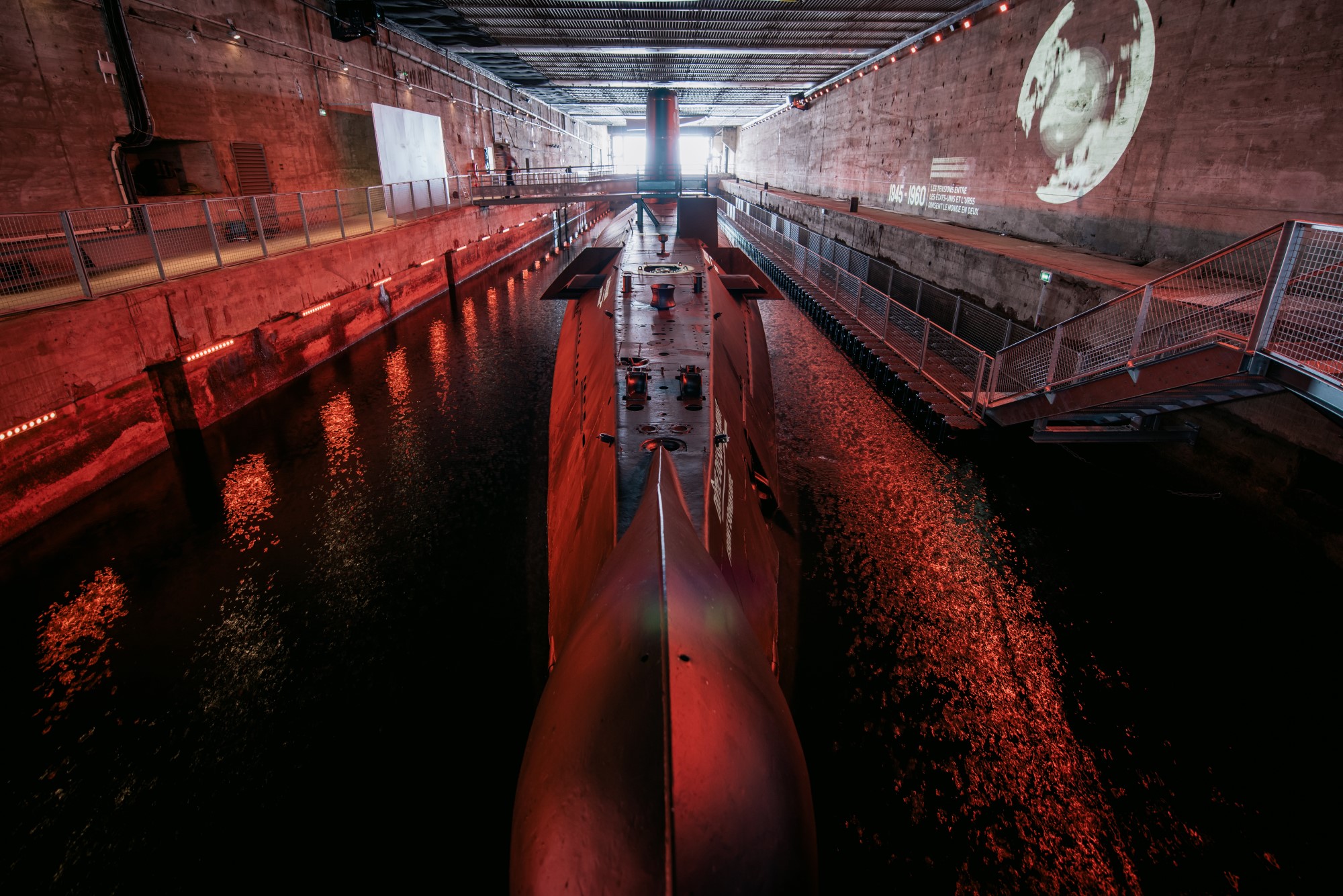 Sous-marin Espadon pris au niveau de la proue éclairé par des spots rouges.