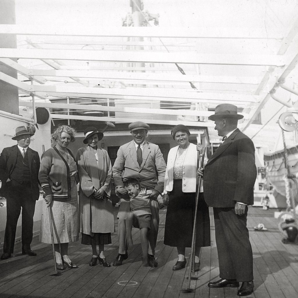 Photographie en noir et blanc illustrant des passagers sur le pont d'un paquebot avec un jeu de shuffle board.