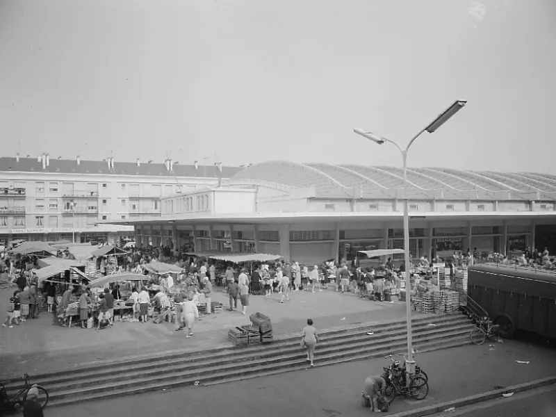 Photographe : Paul Lemasson. Collection Saint-Nazaire Agglomération Tourisme - Écomusée. Fonds Lemasson. Une foule se presse devant les halles couvertes de Saint-Nazaire, un jour de marché.