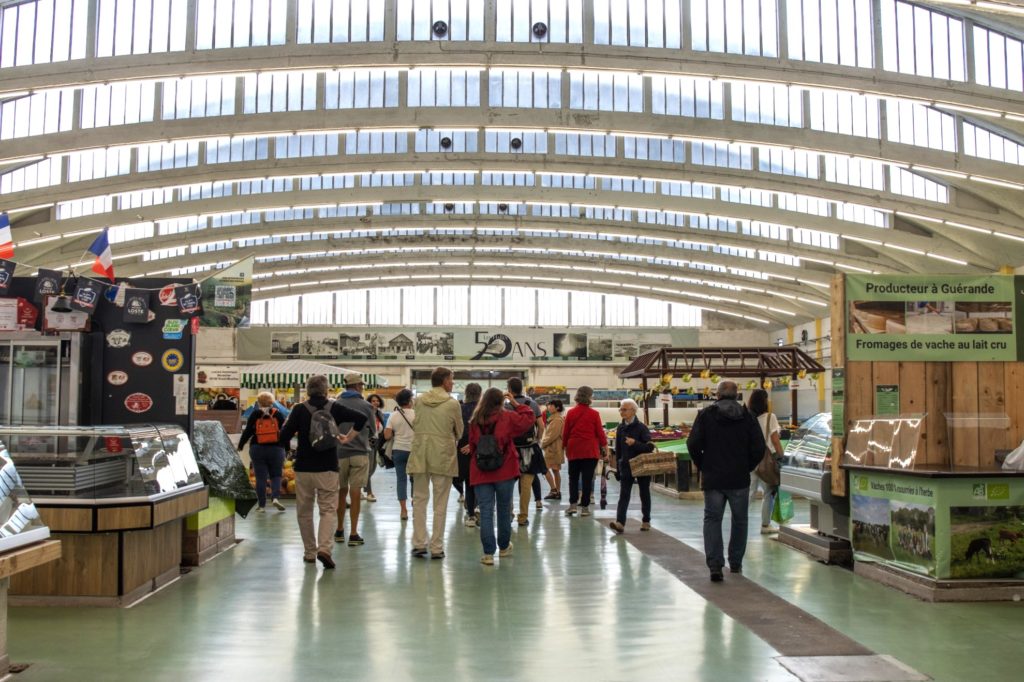 Groupe de visiteurs de dos à l'intérieur du marché lors d'une visite des halles de Saint-Nazaire.