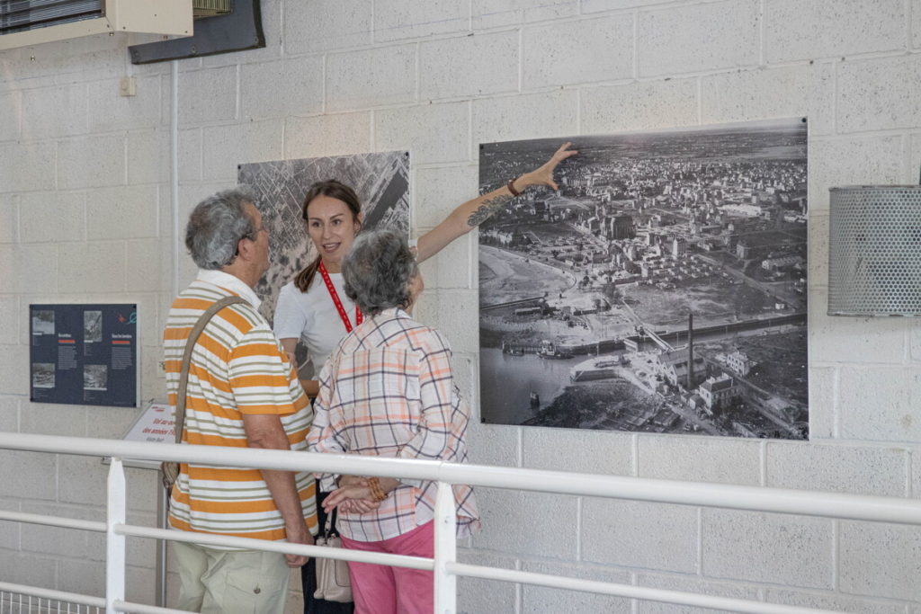 Une médiatrice de l'Écomusée présente l'exposition photographique temporaire "Saint-Nazaire, vue d'en haut" à des visiteurs.