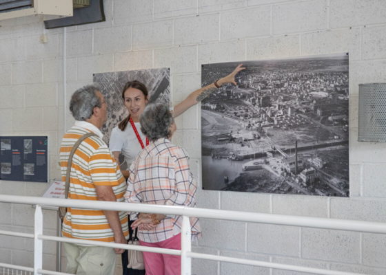 Une médiatrice de l'Écomusée présente l'exposition photographique temporaire "Saint-Nazaire, vue d'en haut" à des visiteurs.