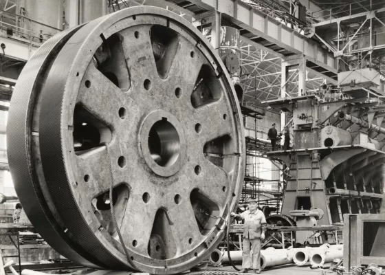 Photographe : inconnu. Collection Saint-Nazaire Agglomération Tourisme - Écomusée. Fonds Chantiers de l’Atlantique. Un ouvrier devant une roue de réducteur d'un groupe turbo-réducteur principal de France (1962).