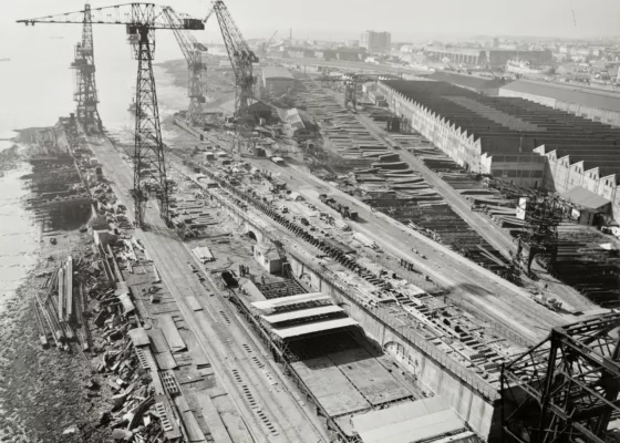 Photographe : inconnu. Collection Saint-Nazaire Agglomération Tourisme - Écomusée. Fonds Chantiers de l’Atlantique. Photographie noir et blanc de la cale de construction du paquebot France en octobre 1957.