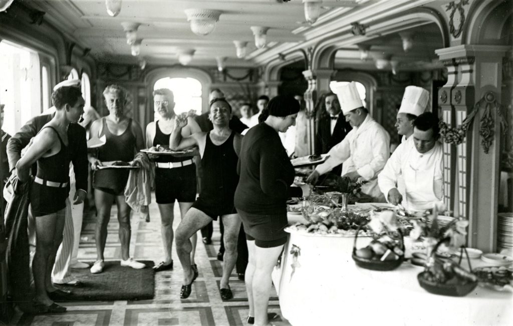 Des passagers en maillots de bain déjeunent à un buffet froid dans le café-terrasse de première classe du paquebot France (1912), le 16 février 1932.