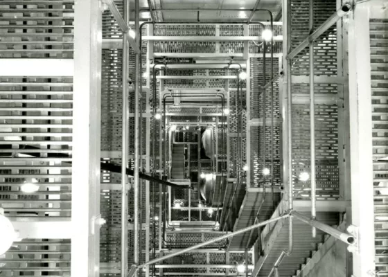 Photographe : Philippe Baudry. Collection Saint-Nazaire Agglomération Tourisme - Écomusée. Fonds Chantiers de l’Atlantique. Photographie noir et blanc représentant en plongée les escaliers du panneau de chaufferie du paquebot France (1962).