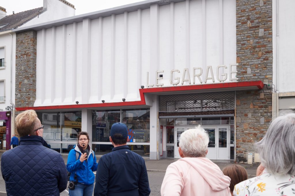Un guide s'adresse à son public lors d'une visite devant le Garage de Saint-Nazaire.