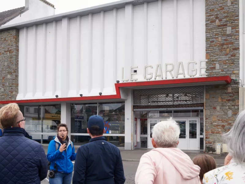 Photographe : Rudy Burbant. Saint-Nazaire Agglomération Tourisme Un guide s'adresse à son public lors d'une visite devant le Garage de Saint-Nazaire.