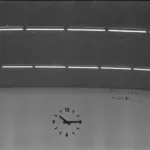 Photographie noir et blanc du toit des halles centrales et de son horloge de Saint-Nazaire vu de l'intérieur.