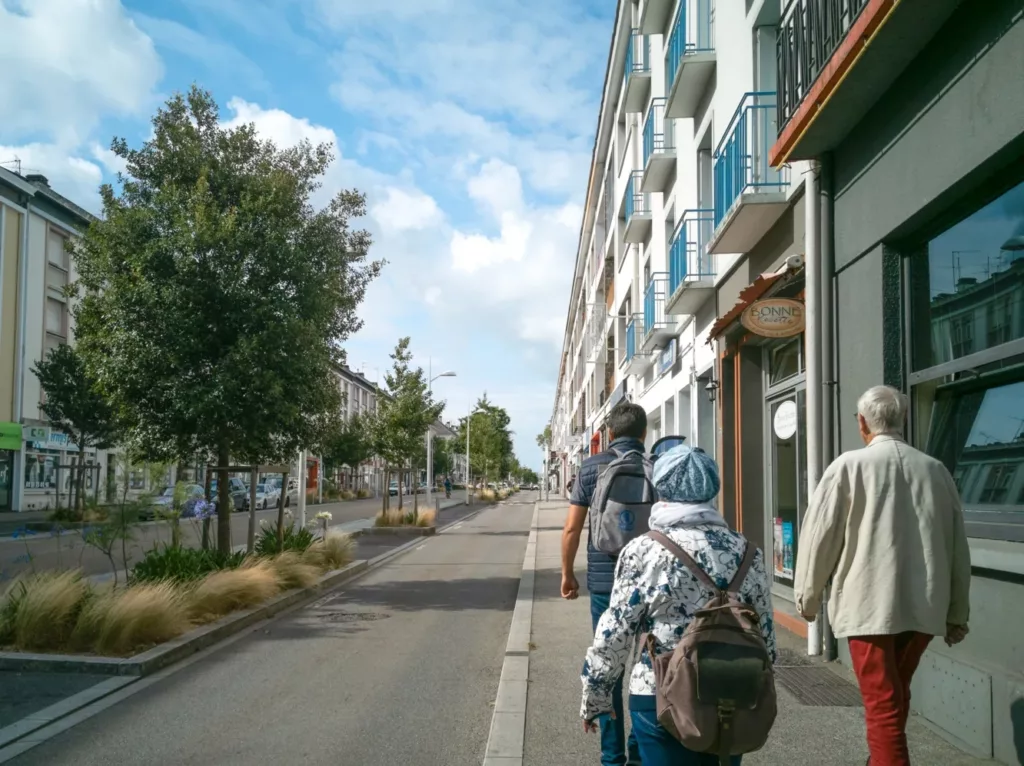 Visiteurs et médiateur vus de dos lors d'une visite commentée avenue de la République lors d'une randonnée urbaine sur la Reconstruction.