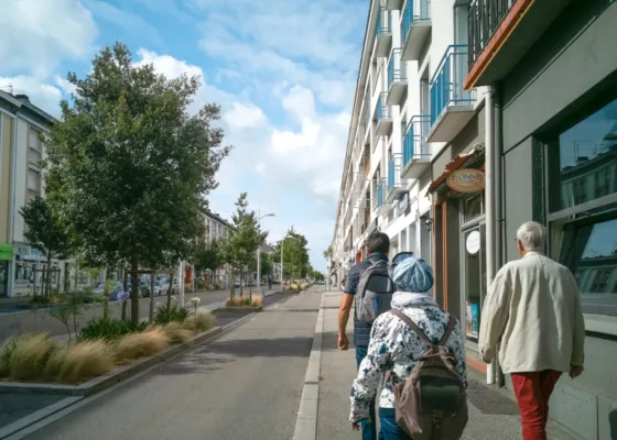 Visiteurs et médiateur vus de dos lors d'une visite commentée avenue de la République lors d'une randonnée urbaine sur la Reconstruction.