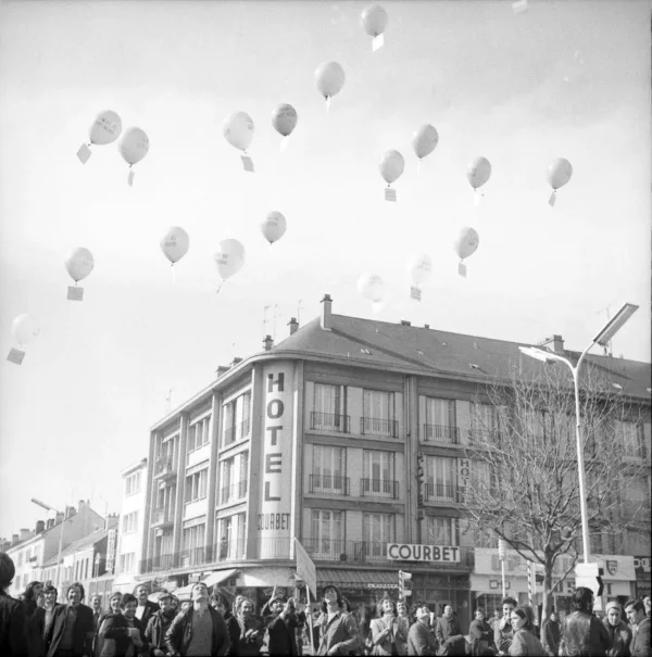 Photographie en noir et blanc représentant une foule rassemblée lors d'un lâcher de ballons lors d'une manifestation, sur la place de l'hôtel de ville à Saint-Nazaire.